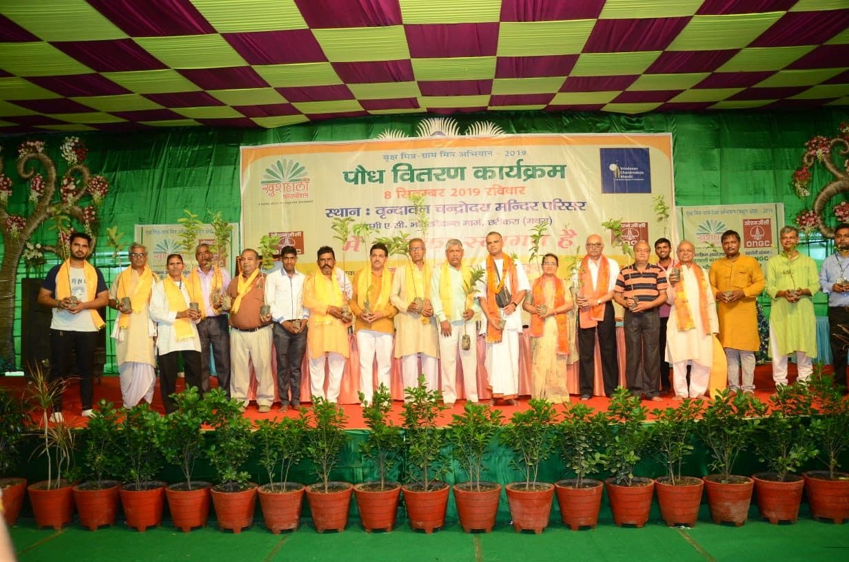 Guests on a stage lined with fruit saplings at a 2019 distribution camp
