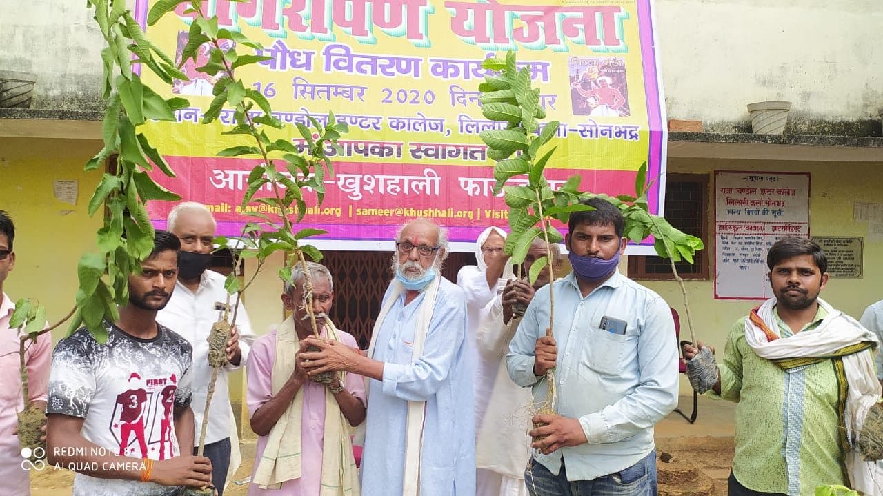 Farmers holding fruit saplings at a September 2020 camp during the pandemic