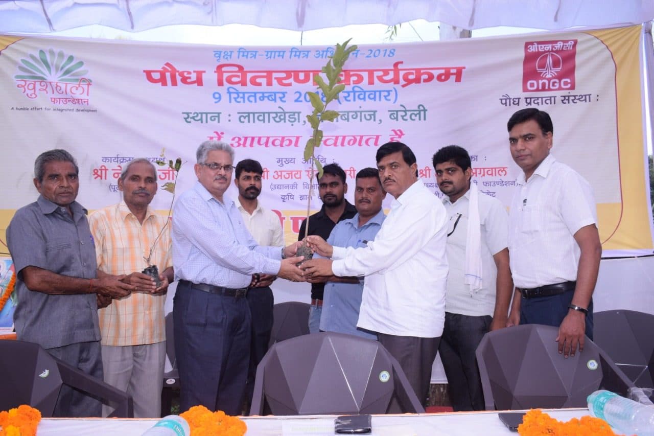 A farmer receives a fruit sapling on stage at the 2018 distribution camp in Bareilly, supported by ONGC